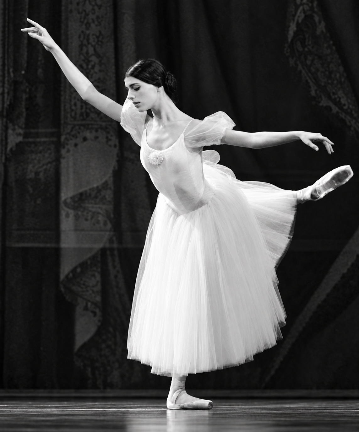 Sara Ezzell performing an arabesque in a black-and-white stage photograph